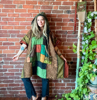 Person wearing a colorful patchwork dress against a brick wall with plants.
